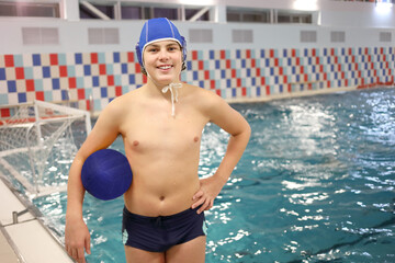 Portrait of happy young man with ball for water polo in front of the pool