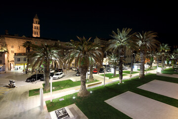 Alley decorated with palm trees and flower beds in the Croatian city of Split at the evening