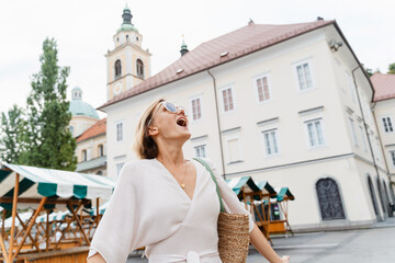 Smiling woman wearing stylish outfit walking on street of Ljubljana old town, Slovenia.Travel Europe - 762269515