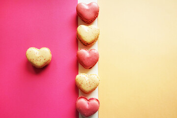 Macarons in the shape of hearts on a pink and yellow background