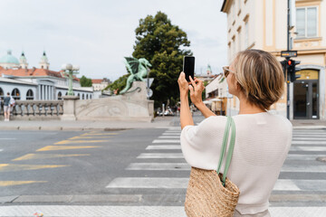 Woman taking photo on smartphone of Dragon bridge (Zmajski most), symbol of Ljubljana, Slovenia - 762270114