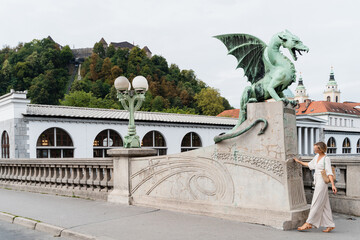 Young woman taking photo in front famous Dragon bridge in Ljubljana. Travel Explore Slovenia, Europe