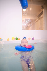 A baby is in a bathtub with a blue float on his head