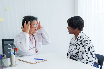 Obstetrician-gynecologist in dialogue with patient, hands to head in gesture of explanation, office setting denotes professional medical advice.Senior gynecologist listens actively to patient concerns