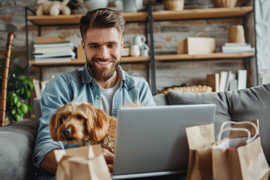 Cheerful man doing online shopping from a laptop sitting on the sofa with his dog in hand at home. Horizontal composition.