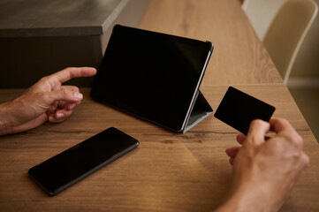 Man using a digital tablet with mockup touch screen and black empty credit card, shopping online on internet web sites
