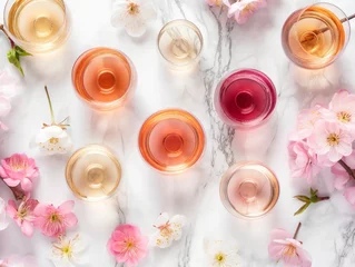 Behang Top view of various wine glasses surrounded by delicate spring flowers on a marble background, symbolizing a refined tasting event © cherezoff