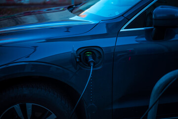 Charging a modern electric car on the street in the evening, which are the future of the Automobile