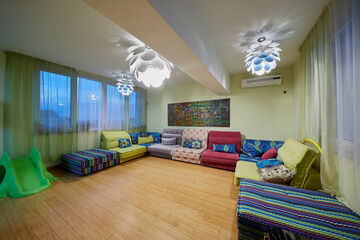 Interior of spacious room with many sofas at walls and three chandeliers.