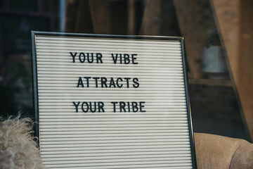 Your vibe attracts your tribe motivational quote on a board.