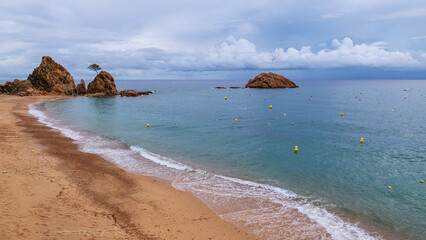 Golden beach in small Spanish town with rocks and island