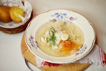 Plate of noodle soup decorated with half egg and dill on table.