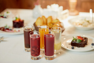 Fototapeta na wymiar Several kinds of fruit beverages in glasses and cakes on table, shallow dof.