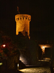 Castle tower lit up at night in small Spanish town