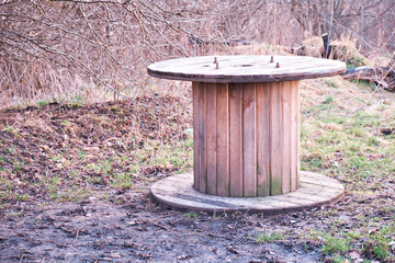 An empty wooden coil with a power cable.