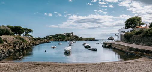 Serene bay in Spain with moored boats and island and trees in background