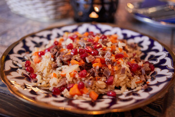 Plate with fresh pilaf with meat and pomegranate seeds.