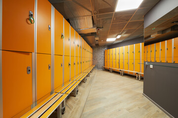 Locker room with orange lockers at fitness center.