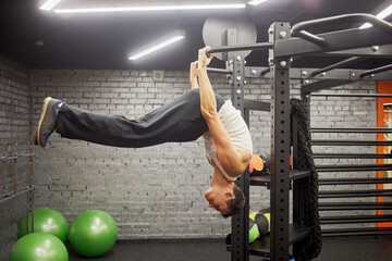 Man doing exercises on horizontal bar in gym hall.
