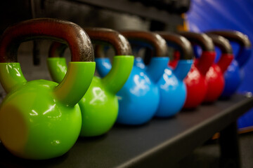 Kettlebells on rack in gym hall.