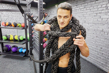 Portrait of man with fitness rope in gym.