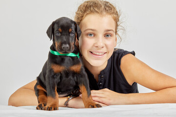 Girl and doberman puppy with green band on neck.