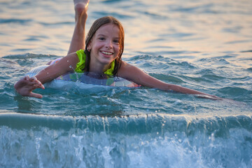 Portrait of a smiling child, a girl on an inflatable ring in the sea or pool.