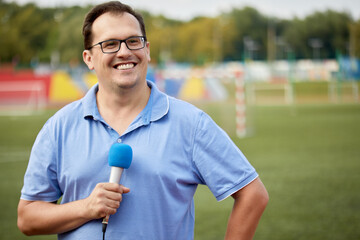 Smiling man with microphone is reporting from stadium.