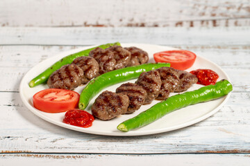 Grilled meat balls. Turkish grilled meatballs with roasted peppers and tomatoes on wooden background