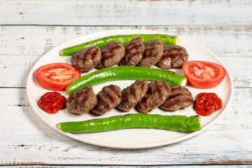 Grilled meat balls. Turkish grilled meatballs with roasted peppers and tomatoes on wooden background. Close up