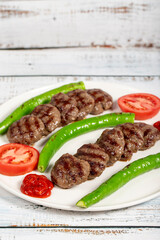 Grilled meat balls. Turkish grilled meatballs with roasted peppers and tomatoes on wooden background