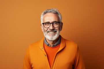 Happy smiling elderly man with short beard and glasses standing in the living room - obrazy, fototapety, plakaty