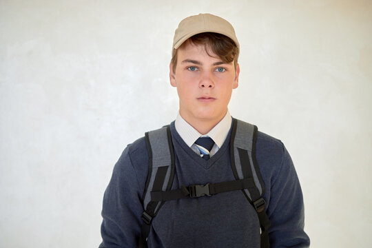 Portrait of schoolboy in cap with rucksack.