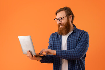 Middle aged redhaired guy with beard using laptop in studio
