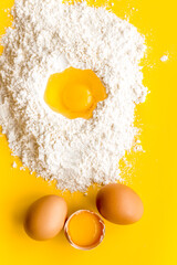 Making dough concept. Pile of flour and eggs on yellow background top view