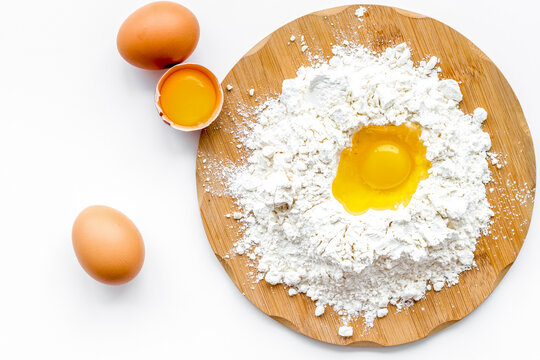 Making dough concept. Pile of flour and eggs on white background top view copy space