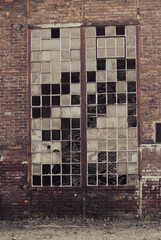 Abandoned factory building with broken glass door and rusty metal lattice