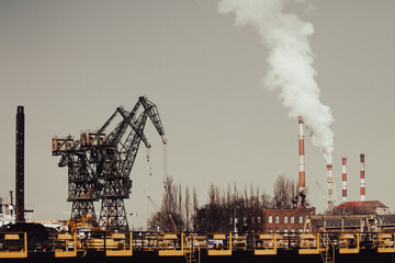 Industrial landscape with cranes and smoking chimneys. 