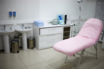 Interior of beauty parlour, pink cosmetology armchair and equipment.
