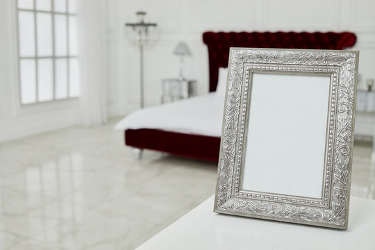 Photo frame on table in spacious bedroom.