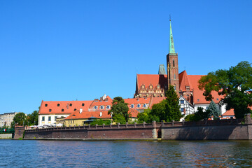 The Cathedral Island (polish: Ostrow Tumski), the oldest part of the city of Wrocław, Poland. View from the boat trip on Oder river. Collegiate Church of the Holy Cross and St. Bartholomew. - obrazy, fototapety, plakaty