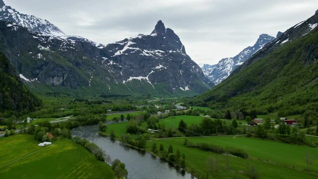 Dramatic, snowy mountain Romsdalshornet, Rauma River, and trees in Romsdalen Valley, Rauma, Norway