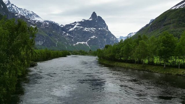 Dramatic, snowy mountain Romsdalshornet, Rauma River, and trees in Romsdalen Valley, Rauma, Norway