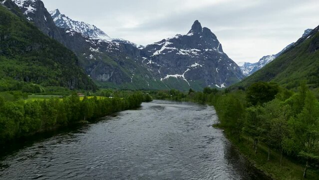 Dramatic, snowy mountain Romsdalshornet, Rauma River, and trees in Romsdalen Valley, Rauma, Norway