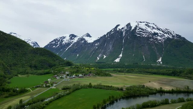 Dramatic, snowy mountain Setnesfjellet, Rauma River, and trees in Romsdalen Valley, Rauma, Norway