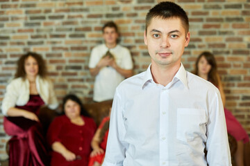 Portrait of young man against family sitting on sofa in room.