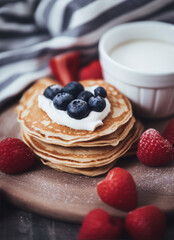 Stack of pancakes topped with blueberries and whipped cream. Sweet breakfast treat.
