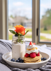 Breakfast tray with pancakes, whipped cream, berries, and a rose.
