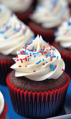 Close-up of red velvet cupcakes with white frosting and red white and blue sprinkles.