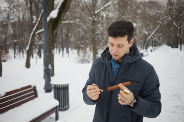 Man lighting cigar with burning match in winter park.